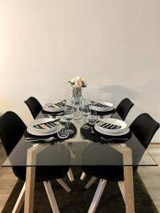 a dining table with black chairs and plates and a vase with flowers at Modern Apartment City Centre in Rovaniemi