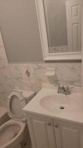 Un baño blanco con inodoro y lavabo. en Room in a Beach House with King Size bed in a landlord hosted three bedroom apartment, en Edgemere