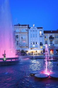 uma fonte na água em frente aos edifícios em ATLAS HOUSE Luxury Suites em Plovdiv