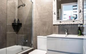 a bathroom with a toilet and a sink and a mirror at AMARA Family & Surf with Oceanview and Pool in Tarifa