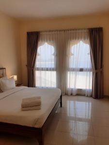 a bedroom with a bed and two large windows at Hala Holiday Homes- Bab Al Bahr Residence, Al Marjan Island in Ras al Khaimah