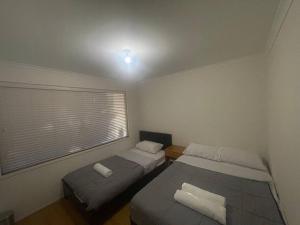 two beds in a small room with a window at Y&Y Holiday House in Craigieburn