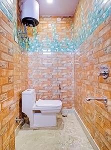 baño con aseo y pared de piedra en Stay with Palace Near- Anand Vihar Station, en Nueva Delhi