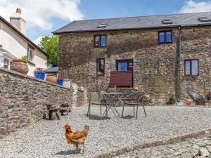 a chicken standing in front of a stone house at 2 Bed in South Molton 78303 in Kings Nympton
