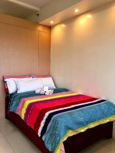 a bed with a colorful blanket on it in a room at Wind Suites in Tagaytay