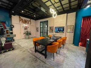 曼谷的住宿－Prince Theatre Heritage Stay Hostel - Silom，一间带桌子和橙色椅子的用餐室