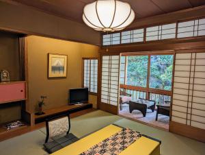 a living room with a television and a large window at Kinosaki Yamamotoya in Toyooka