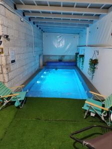 an indoor swimming pool with two chairs and a pool at אחוזת דולב Dolev estate הווילה in Zanoaẖ