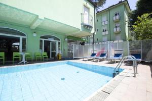 a swimming pool with chairs and a building at Residence Eurogarden in Rimini