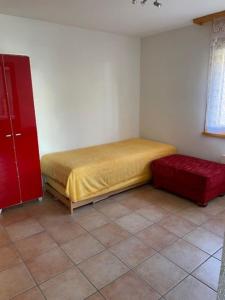 - une chambre avec un lit et un pouf rouge dans l'établissement Résidence Castel Club Leysin Parc, à Leysin