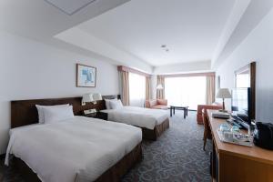 宮古島にあるホテルアトールエメラルド宮古島のベッド2台とテレビが備わるホテルルームです。