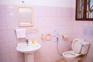 różowa łazienka z toaletą i umywalką w obiekcie Asante Home w mieście Arusza