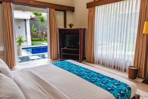 - une chambre avec un lit et une télévision dans l'établissement The Mutiara Jimbaran Boutique Villas, à Jimbaran