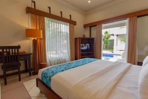 - une chambre avec un lit, un bureau et une fenêtre dans l'établissement The Mutiara Jimbaran Boutique Villas, à Jimbaran