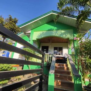 une maison verte avec des escaliers menant à la porte d'entrée. dans l'établissement Bungalow in Holidays Beach Resort, à Bolinao