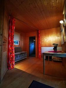 a room with a couch and a table with red curtains at Hide in the nature – cozy lakeside saunacottage in Rannaküla