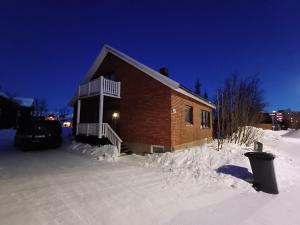 une maison est couverte de neige la nuit dans l'établissement Kiruna accommodation Läraregatan 19 b, à Kiruna