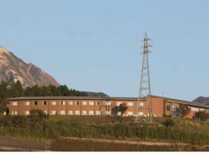 a building in front of a mountain with a tower at Aso Canyon Terrace & Lodge in Minami Aso