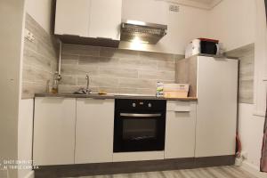 una cocina con armarios blancos y horno negro en Appartement avec un grand parking, en Montélimar