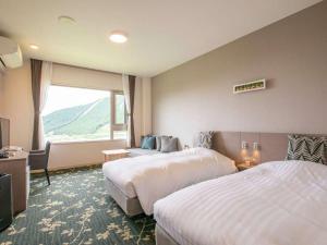 a hotel room with two beds and a window at Aso Canyon Terrace & Lodge in Minami Aso