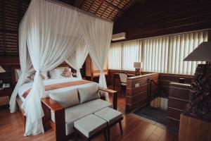 a bedroom with a canopy bed and a chair at Amazing 1 Bedroom Villa in Ubud in Ubud