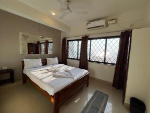 1 dormitorio con 1 cama con sábanas blancas y ventanas en Baga Beach Sunset, en Baga