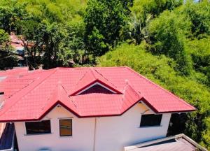 un techo rojo en una casa blanca con árboles en Spacious House in Talamban, Cebu City, en Cebú