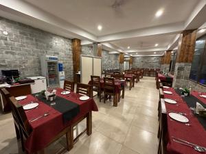 un comedor con mesas y sillas con mantel rojo en Gezellig Inn - Magic Mountain, en Kasol