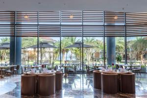 KOI Resort & Residence Da Nang في دا نانغ: مطعم بطاولات وكراسي ونوافذ كبيرة