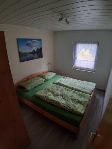 1 dormitorio con 1 cama con edredón verde y ventana en Ferienhäuser - Unter den Kiefern NR 23 oder Nr 27, en Marienfelde