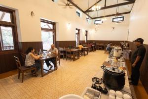 un grupo de personas sentadas en mesas en un restaurante en Scarlet Resort, en Matheran