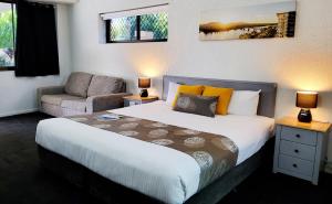 a bedroom with a bed and a couch and a chair at Archer Park Motel in Rockhampton +37 photos