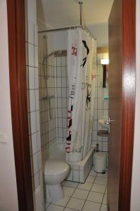 a bathroom with a toilet and a shower curtain at FEWO Seestern 231 in der Lagunenstadt in Neuendorf