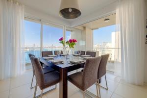 comedor con mesa, sillas y ventanas en Valletta Skyline Serenity Luxury Harbour Views, en Sliema