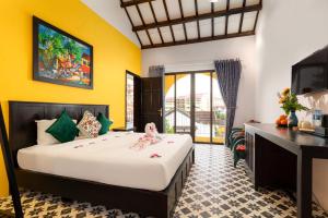 a bedroom with a bed and a desk and a television at Ohana Hoian Villa in Hoi An +79 photos