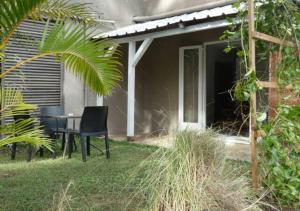 a patio with a table and chairs in a yard at Bikini in Pointe d'Esny