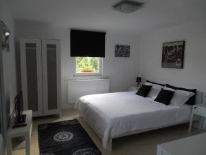 a bedroom with a white bed and a television at Vila Bel Ami in Şelimbăr