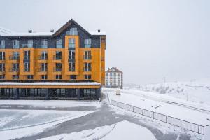 un bâtiment dans la neige devant un bâtiment dans l'établissement New Gudauri Cozy Apartment with a Mountain View, à Goudaouri