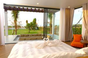 Cama blanca en habitación con ventana grande en Sunset Hill Villa Mũi Né en Phan Thiet