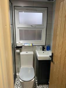 baño con aseo y lavabo y ventana en Private self-contained flat with shared entrance en Londres