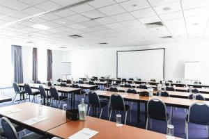 an empty classroom with tables and chairs and a whiteboard at Best Western PLAZA Hotel Grevenbroich in Grevenbroich