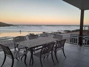 a table and chairs on a balcony overlooking the beach at Beachfront property, Victoria Bay, Garden route in Victoria Bay