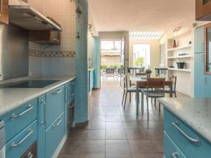 a kitchen with blue cabinets and a table with chairs at Villa Nuria con piscina privada in Playa del Ingles