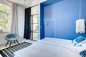 ein blaues Schlafzimmer mit einem Bett und einem Stuhl in der Unterkunft DR Apartments - Cape in Sopot