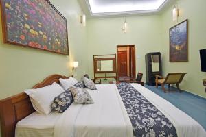 a bedroom with a large bed with pillows at Le Colonial Suites in Puducherry