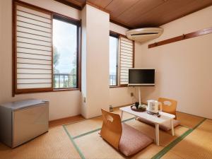 un soggiorno con tavolo, sedie e TV di Hayamasou a Tokamachi