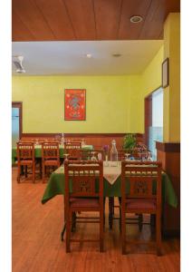 a dining room with a table and chairs and a yellow wall at Hotel Aramana in Kāladi