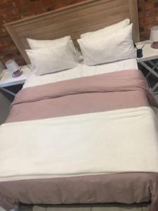 a large bed with white sheets and pillows at Euphoria in Nelspruit