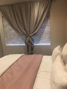 a bed in a bedroom with a window with a curtain at Euphoria in Nelspruit