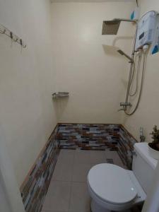 a bathroom with a toilet and a brick wall at Transient in Bria Homes in General Santos